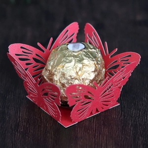Macro view of laser-cut red paper butterfly decorative holder for wedding chocolate