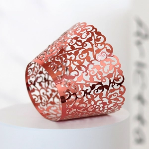 Detail of rose gold cupcake wrapper with laser-cut vine pattern and metallic mirror finish