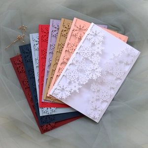 Laser-cut snowflake invitation covers in various colors on elegant tulle background