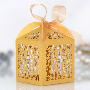 Detail of laser-cut golden favor box with cross pattern and elegant satin ribbon bow