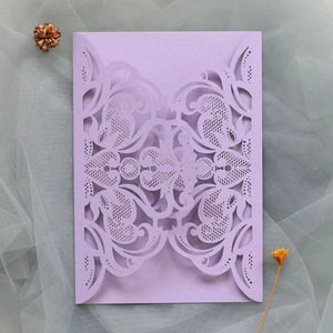 Macro detail of laser-cut lavender lace wedding invitation with intricate floral patterns
