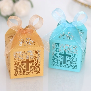 Detail of laser-cut wedding favor boxes with ornate cross patterns and silk ribbons