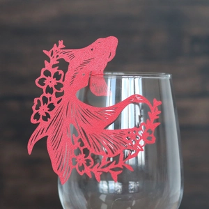 Macro detail of red laser-cut goldfish paper card for wedding wine glass decoration