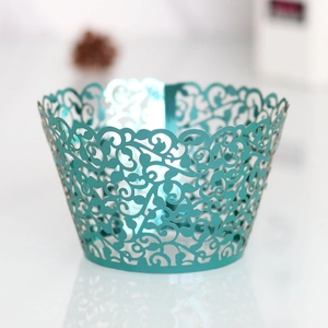 Detail showing teal laser-cut cupcake wrappers with intricate vine and floral hollow patterns