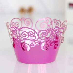 Close-up of laser-cut metallic pink cupcake wrapper with elegant hollow scroll design