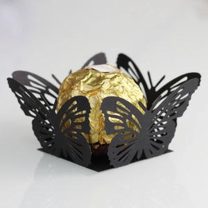 Macro view of laser-cut black butterfly chocolate wrapper with intricate镂空details