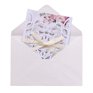 Close-up of laser-cut lace wedding invitation with ribbon and floral insert card