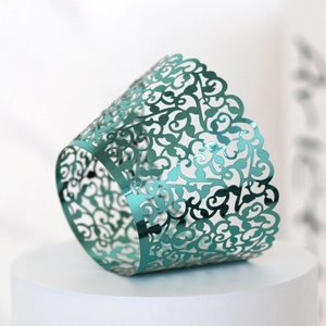 Detail view of laser-cut teal metallic vine lace wrapper for wedding cupcakes