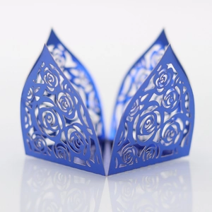 Detailed laser-cut rose pattern on dark blue paper cupcake wrapper for wedding decor
