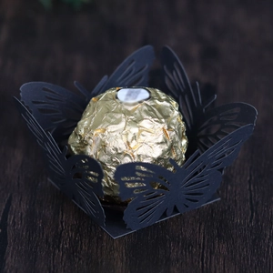 Macro detail of laser-cut black butterfly cupcake wrapper with intricate hollow patterns