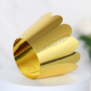Detail of laser-cut gold mirror cupcake wrapper with elegant wavy edge decoration