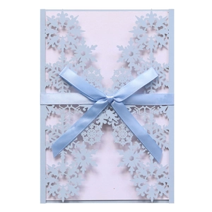Detailed laser-cut snowflake invitation card with blue ribbon bow on white background