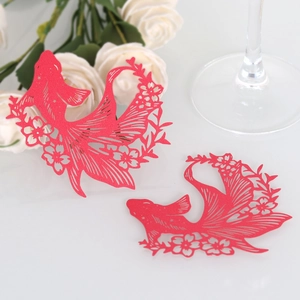 Close-up of laser-cut red goldfish wine glass cards with intricate floral patterns