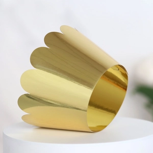 Detail shot of golden crown-shaped cake wrapper with laser-cut hollow wavy lace pattern