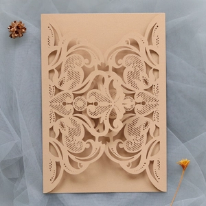 Close-up of laser-cut lace floral pattern on champagne gold wedding invitation cover