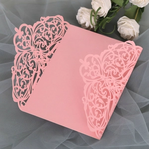 Detail of pink laser-cut hollow lace wedding invitation cover on soft mesh background