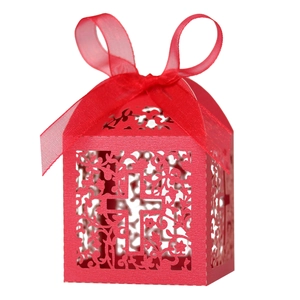 Detail of red laser-cut candy box with floral cross design and silk ribbon bow