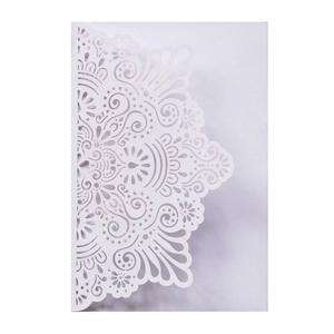 Macro detail of laser-cut floral mandala pattern on white wedding invitation card