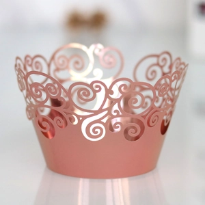 Macro shot of rose gold laser-cut cupcake wrappers with elegant hollow swirl patterns