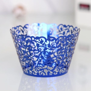 Close-up of laser-cut cupcake wrapper with elegant vine and flower patterns in dark blue
