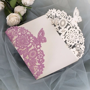 Detail of laser-cut wedding invitation with pink glitter butterfly and rose pattern
