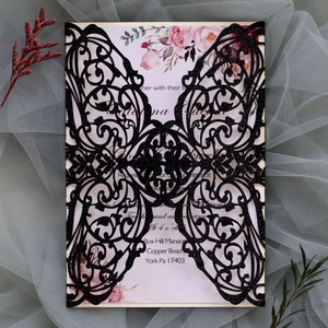Macro view of laser-cut black glitter wedding invitation with floral printed card