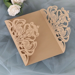 Detail of laser-cut lace pattern on gold wedding invitation cover with floral lace