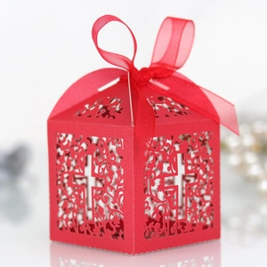 Intricate laser-cut red paper gift box featuring hollow cross and floral vine patterns