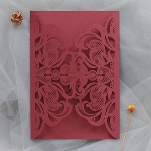 Detailed laser-cut vine patterns on burgundy wedding invitation with elegant floral texture