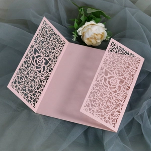 Close-up of laser-cut rose hollow patterns on pink wedding invitation cards with tri-fold design
