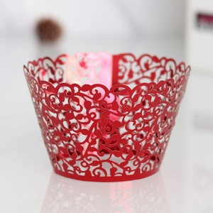 Macro view of red laser-cut cupcake liner with elegant vine floral pattern detail