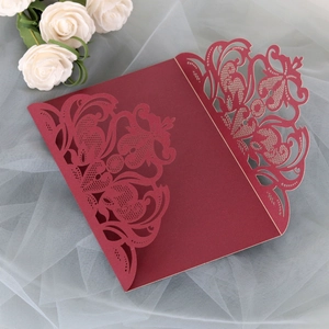 Close-up of laser-cut burgundy wedding invitation with intricate floral hollowed details