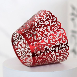 Detail of laser-cut red cupcake wrappers with intricate hollow vine flower patterns