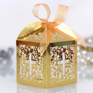 Close-up of golden laser-cut candy box with cross patterns and a satin ribbon bow