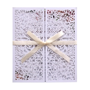 Elegant laser-cut white branch invitation card with beige ribbon bow and floral insert