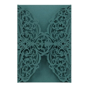 Detail of laser-cut hollow floral pattern on a dark cyan wedding invitation card