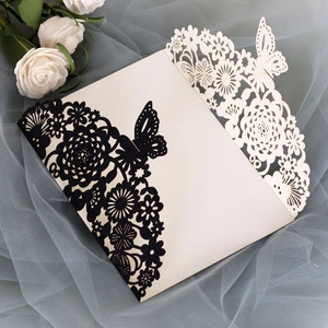 Detailed laser-cut floral and butterfly patterns on cream paper wedding invitation card