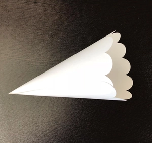 Detail view of white scalloped edge paper flower cone against a black background