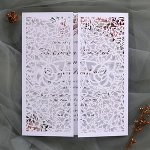 Detail of laser-cut wedding invitation with white floral lace and rose patterns