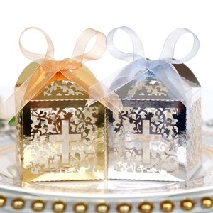 Detail showing laser-cut silver and gold cross gift boxes with ribbons on a decorative plate