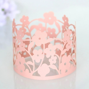 Detail of pink laser-cut floral paper cupcake wrappers with intricate hollow patterns