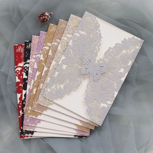 Macro view of laser-cut glitter wedding invitations featuring floral and butterfly patterns