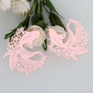Detail view of pink laser-cut goldfish paper cards with intricate floral hollow patterns