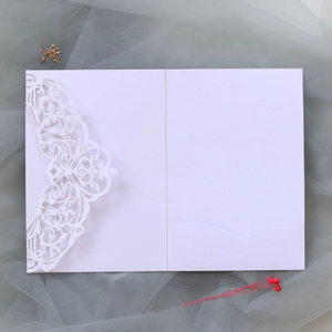 Detailed laser-cut wedding invitation featuring elegant white lace patterns and slots