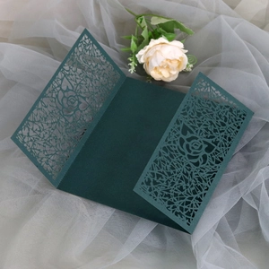 Detail of dark green laser-cut wedding invitation with elegant rose patterns