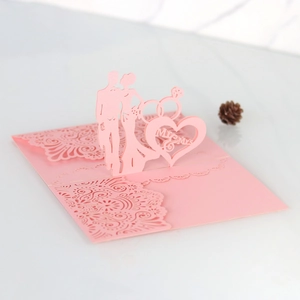 Macro view of pink laser-cut wedding invitation featuring Mr & Mrs heart pattern