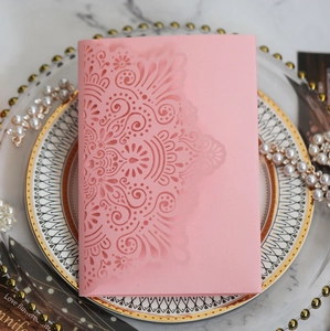 Detailed laser-cut mandala pattern on elegant pink wedding invitation card on a marble surface