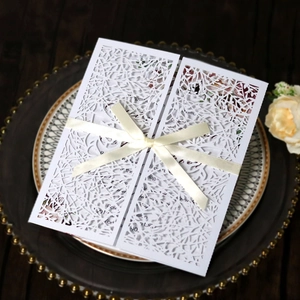 Detail of laser cut wedding invitation with cream ribbon on a vintage tray