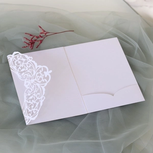 Detailed view of white laser-cut lace invitation cover with floral patterns on mesh fabric