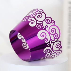 Close-up of purple mirror laser-cut cupcake wrapper with intricate hollow swirl patterns